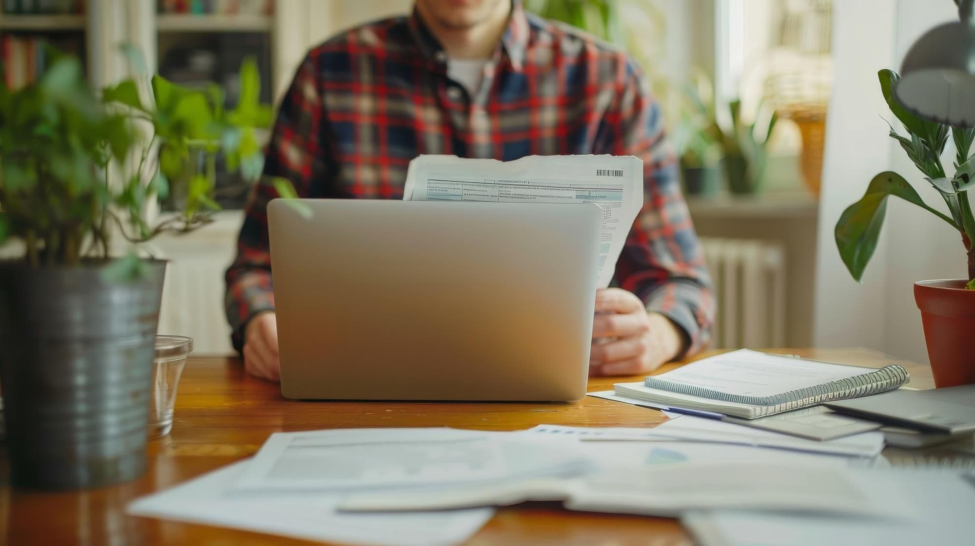 Person calculating tax returns at home with documents and a laptop