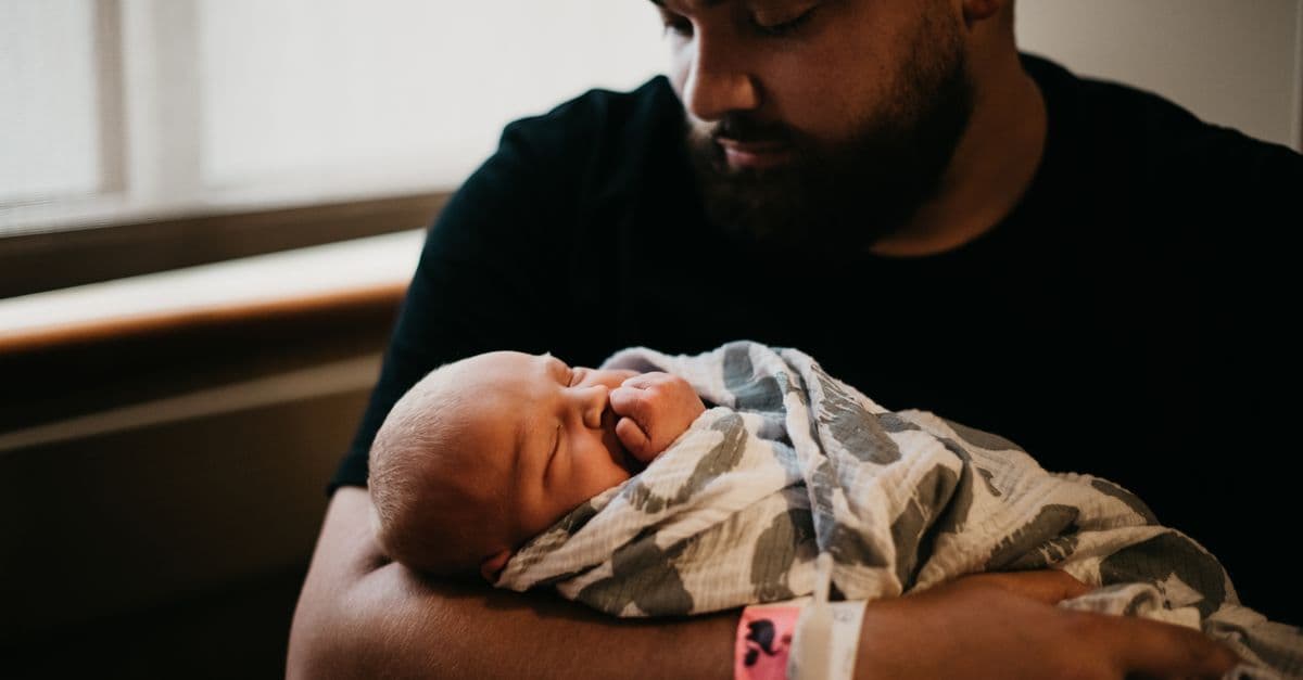Vater hält sein neugeborenes Baby kurz nach der Geburt im Krankenhaus