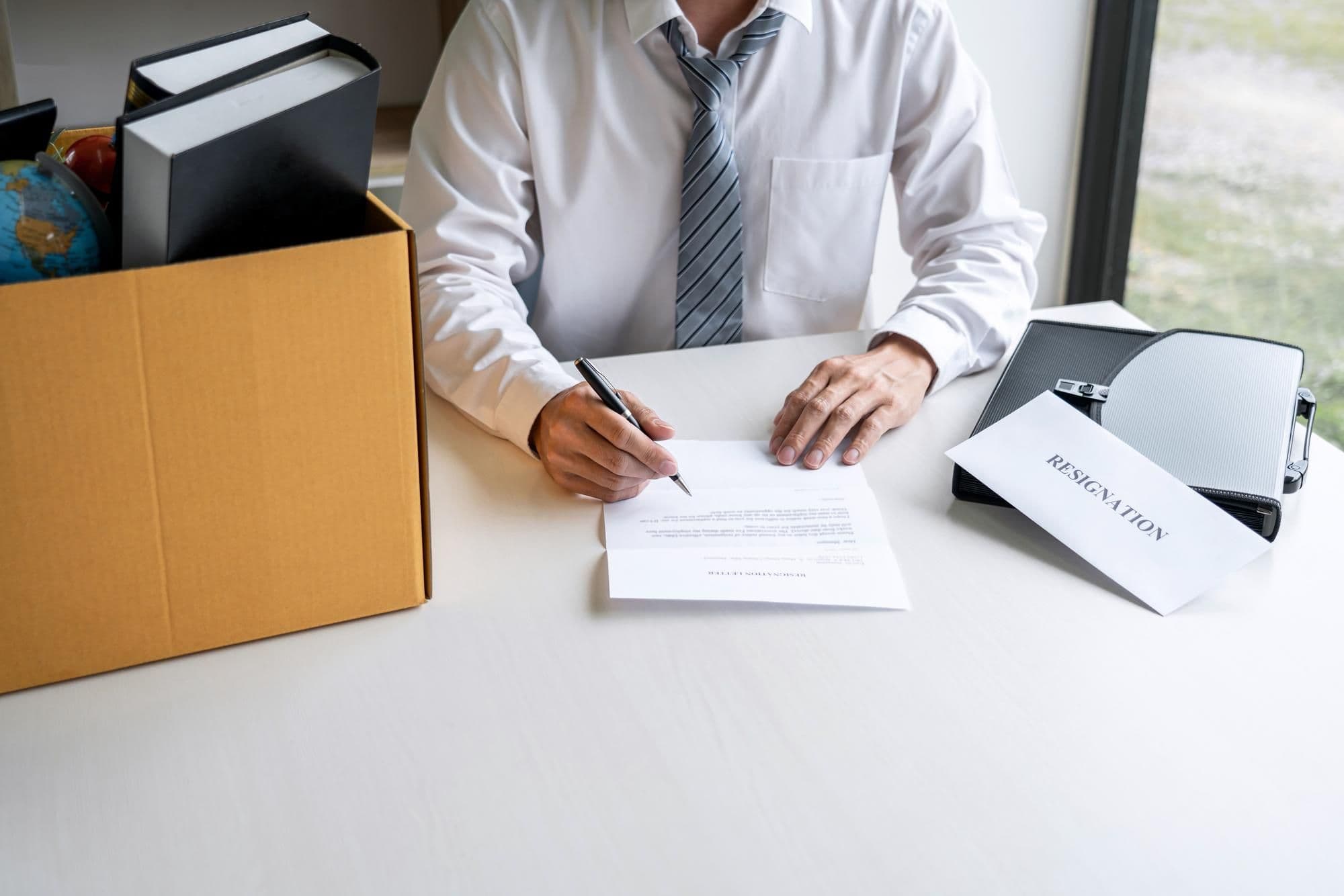 Arbeitnehmer verfasst am Schreibtisch die schriftliche Anforderung für das Arbeitszeugnis