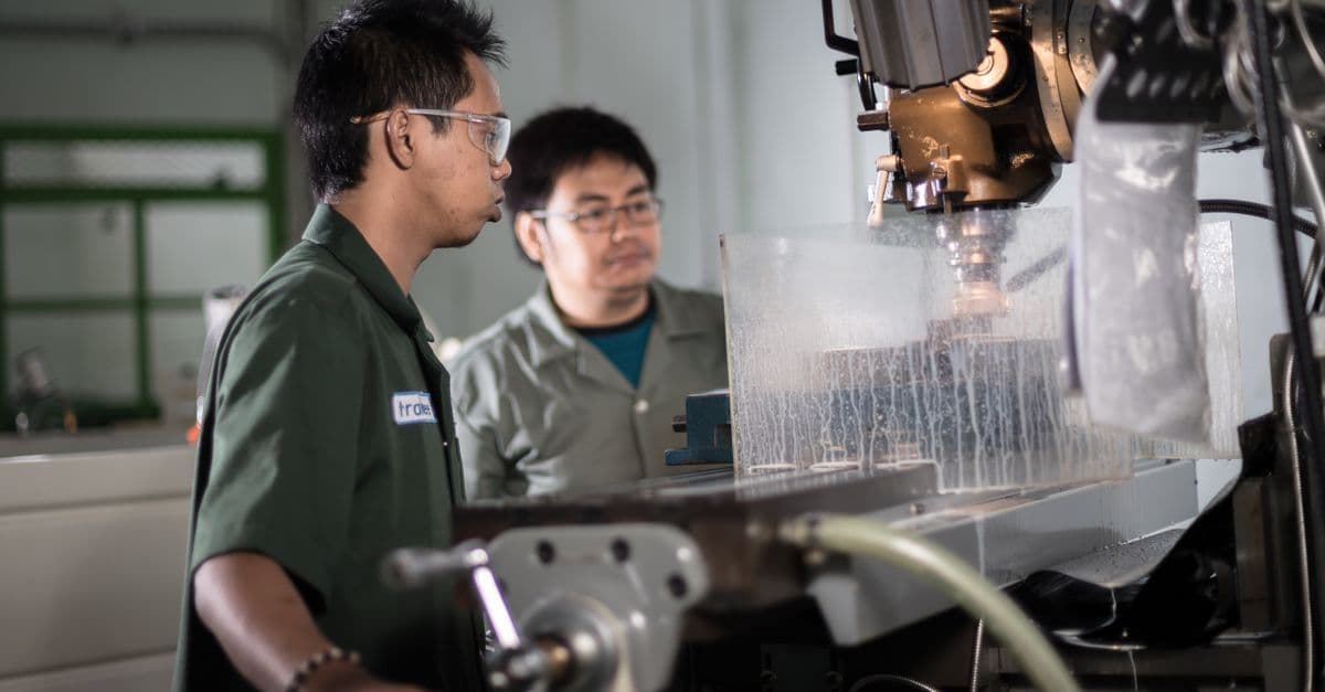 Zwei Techniker bedienen konzentriert eine CNC-Maschine in einer indonesischen Werkstatt