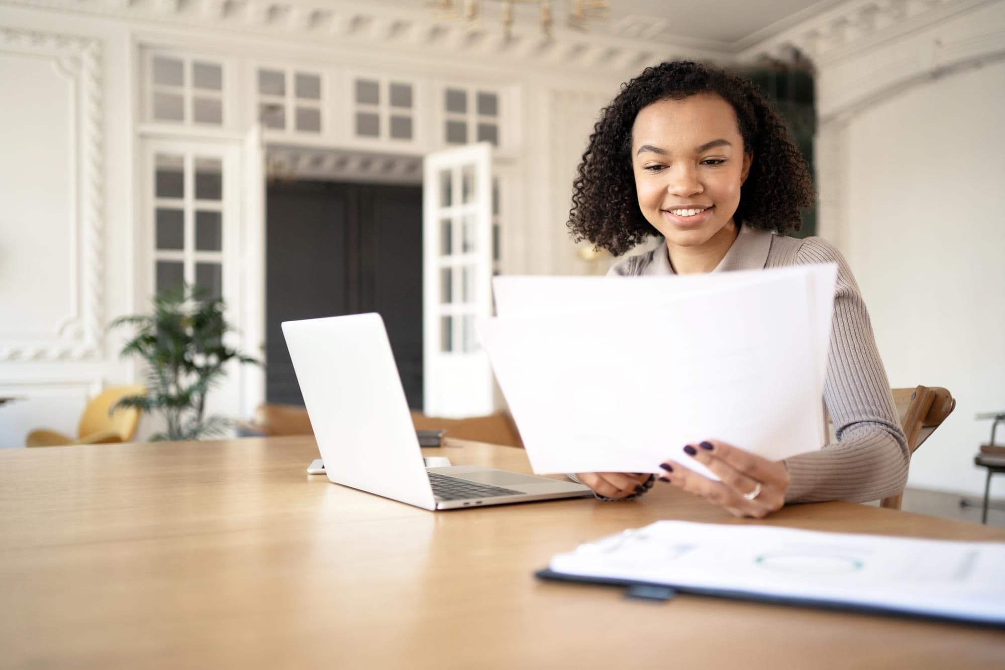 Female student uses laptop on desk chat online video call working with documents in new office