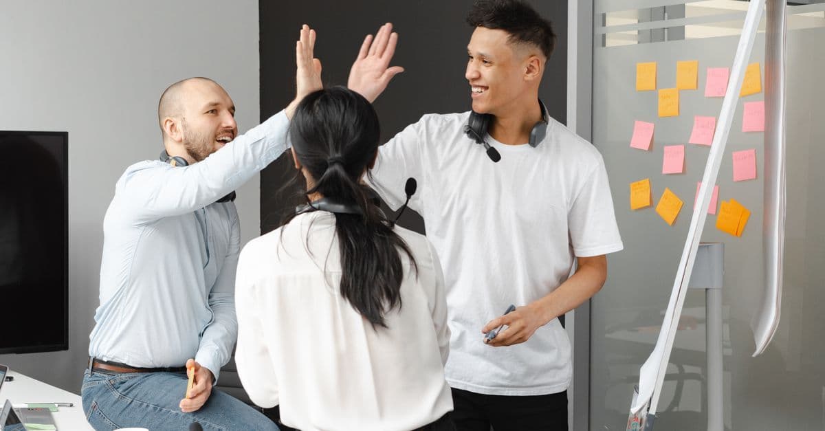 Team von Kolleginnen und Kollegen gibt sich im Büro ein High-Five als Zeichen von Zusammenhalt