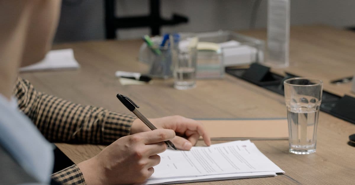 Person unterschreibt ein Arbeitszeugnis-Dokument am Schreibtisch