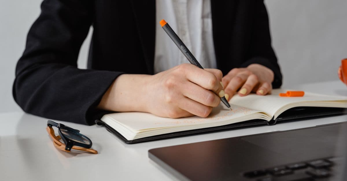 Person schreibt reflektierend in ein Notizbuch, um Stärken und Werte für die berufliche Neuorientierung zu klären