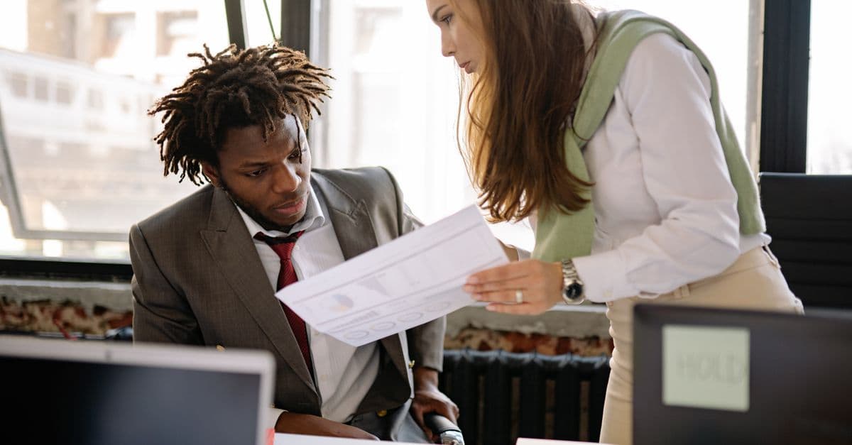 Vorgesetzter im Gespräch mit einem Mitarbeiter im Büro, sinnbildlich für die Fürsorgepflicht des Arbeitgebers