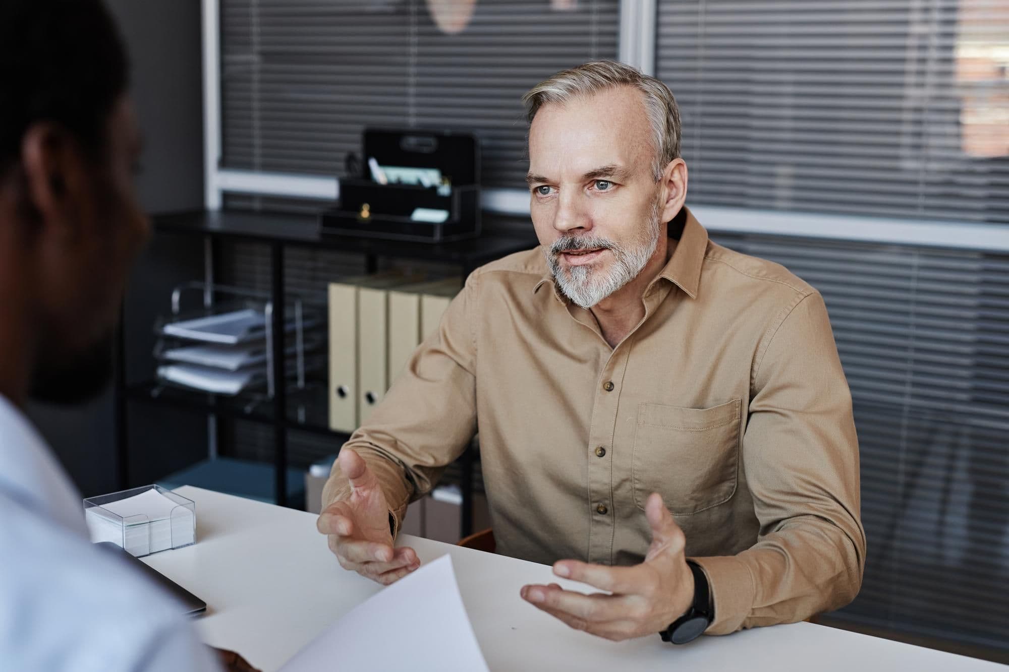 Bearded mature man speaking to recruiter during job interview