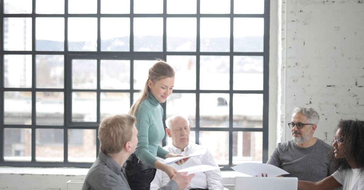 Multiracial coworkers of different ages in casual clothes discussing work plan and current issues at table with laptop in office
