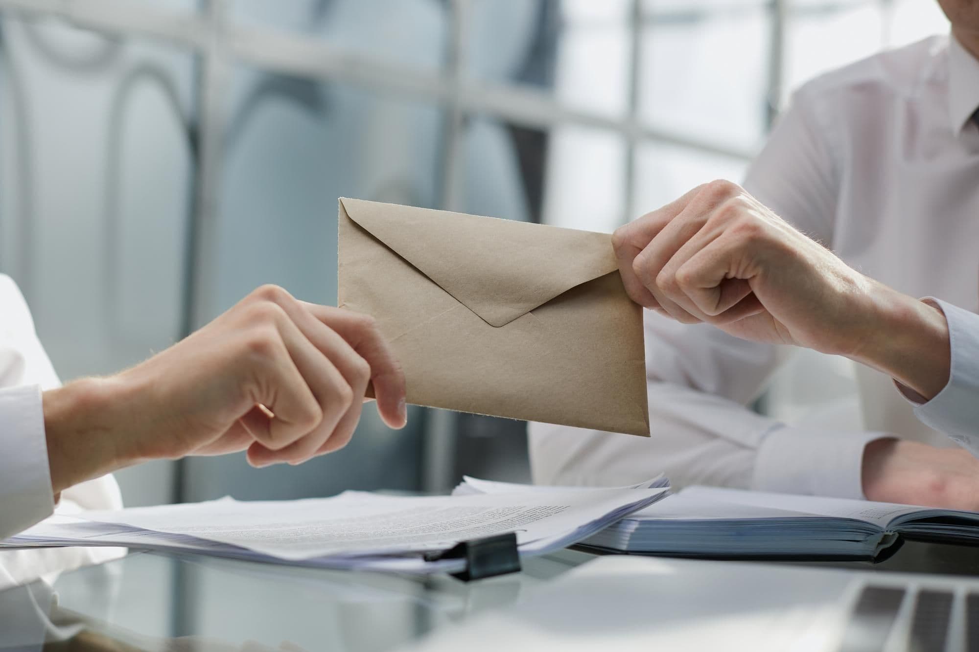 Symbolbild für die Vergütung beim Probearbeiten: Handschlag mit Geldscheinen im Büro