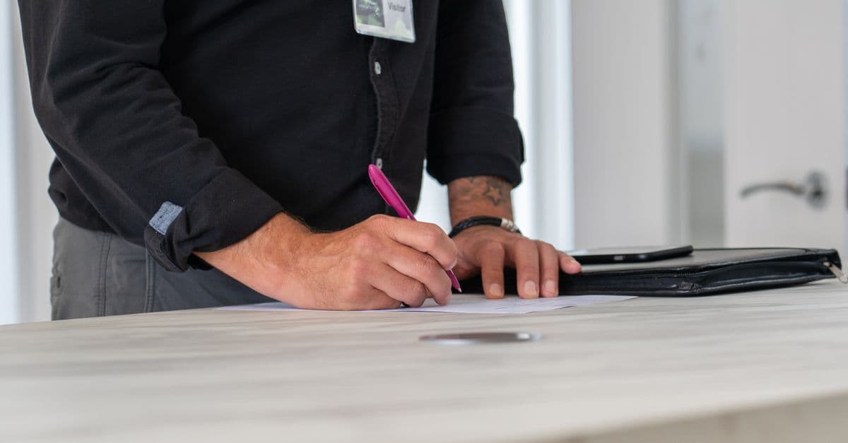 Arbeitnehmer unterschreibt ein Dokument am Schreibtisch als Symbol für den Empfang einer Abmahnung