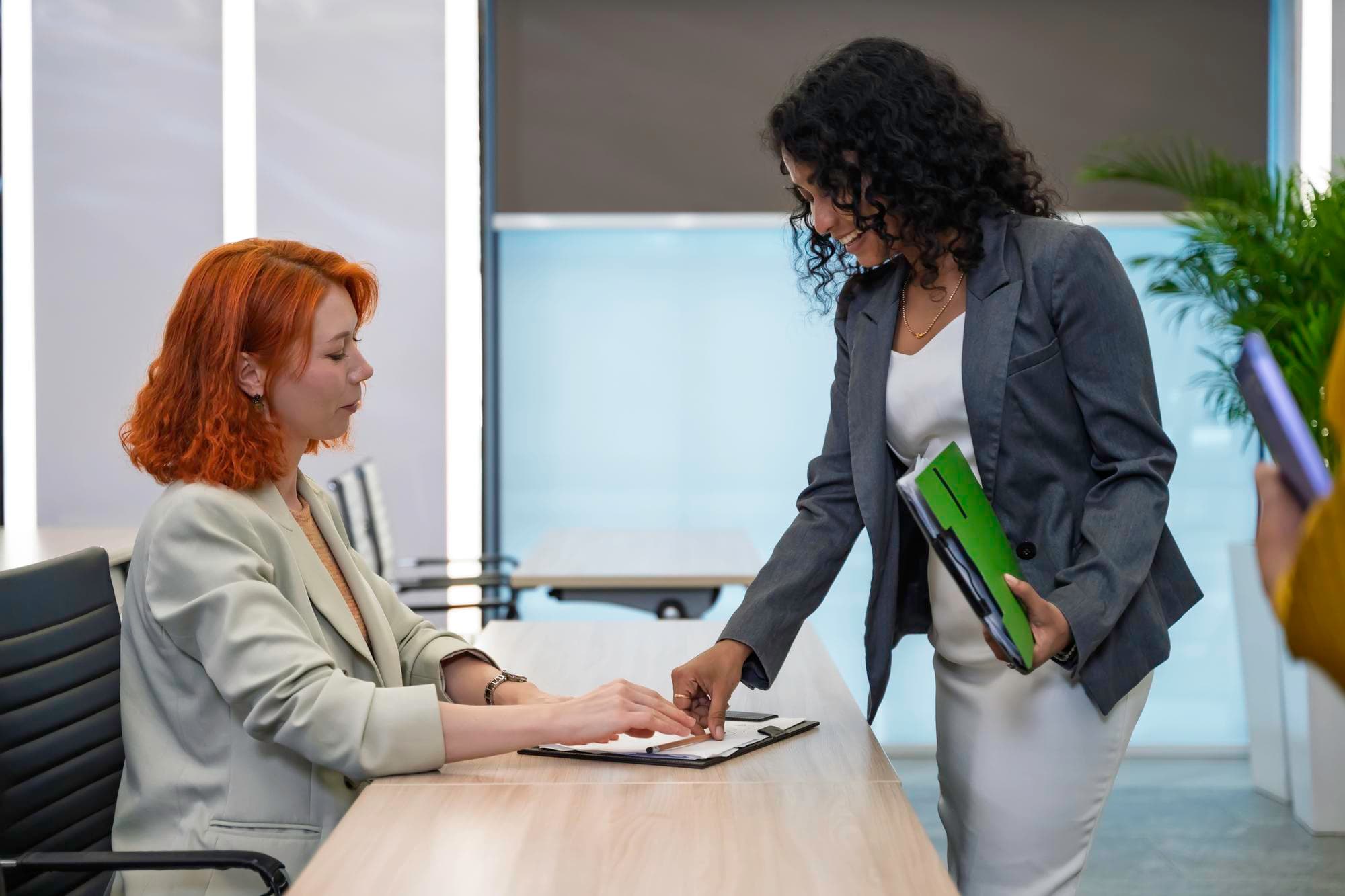 Professional women collaborating on documents in a modern office