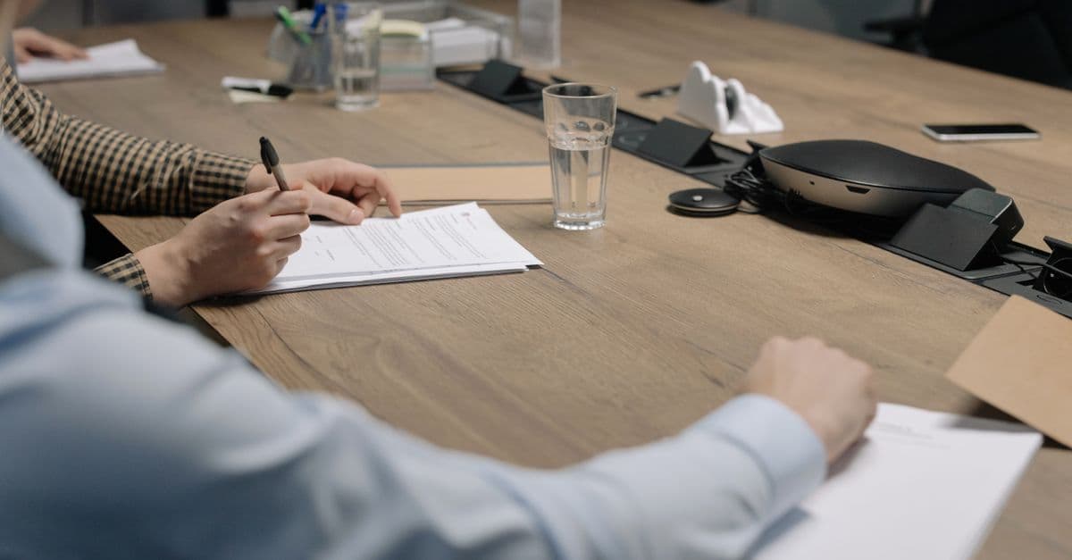 Professional setting of a business meeting with individuals signing documents on a conference table.