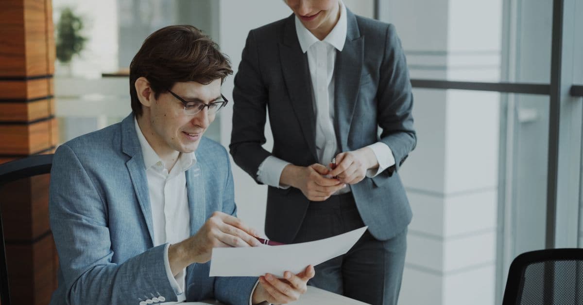 Two business professionals discussing a document in a modern office setting.