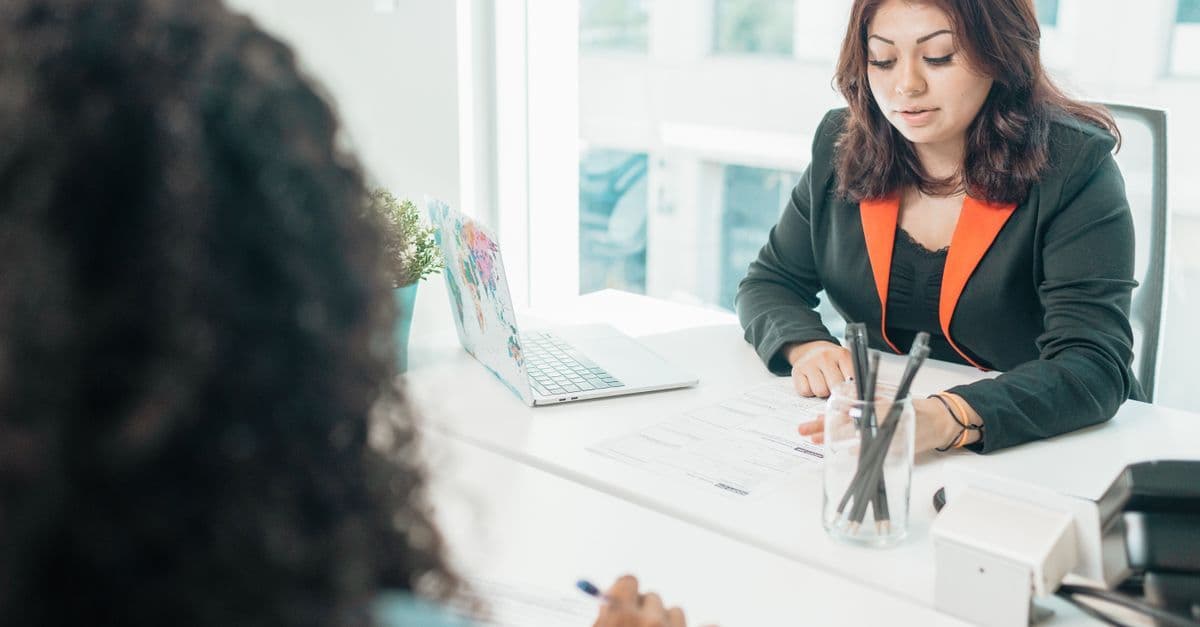 Two colleagues discussing documents during a meeting in a bright modern office.