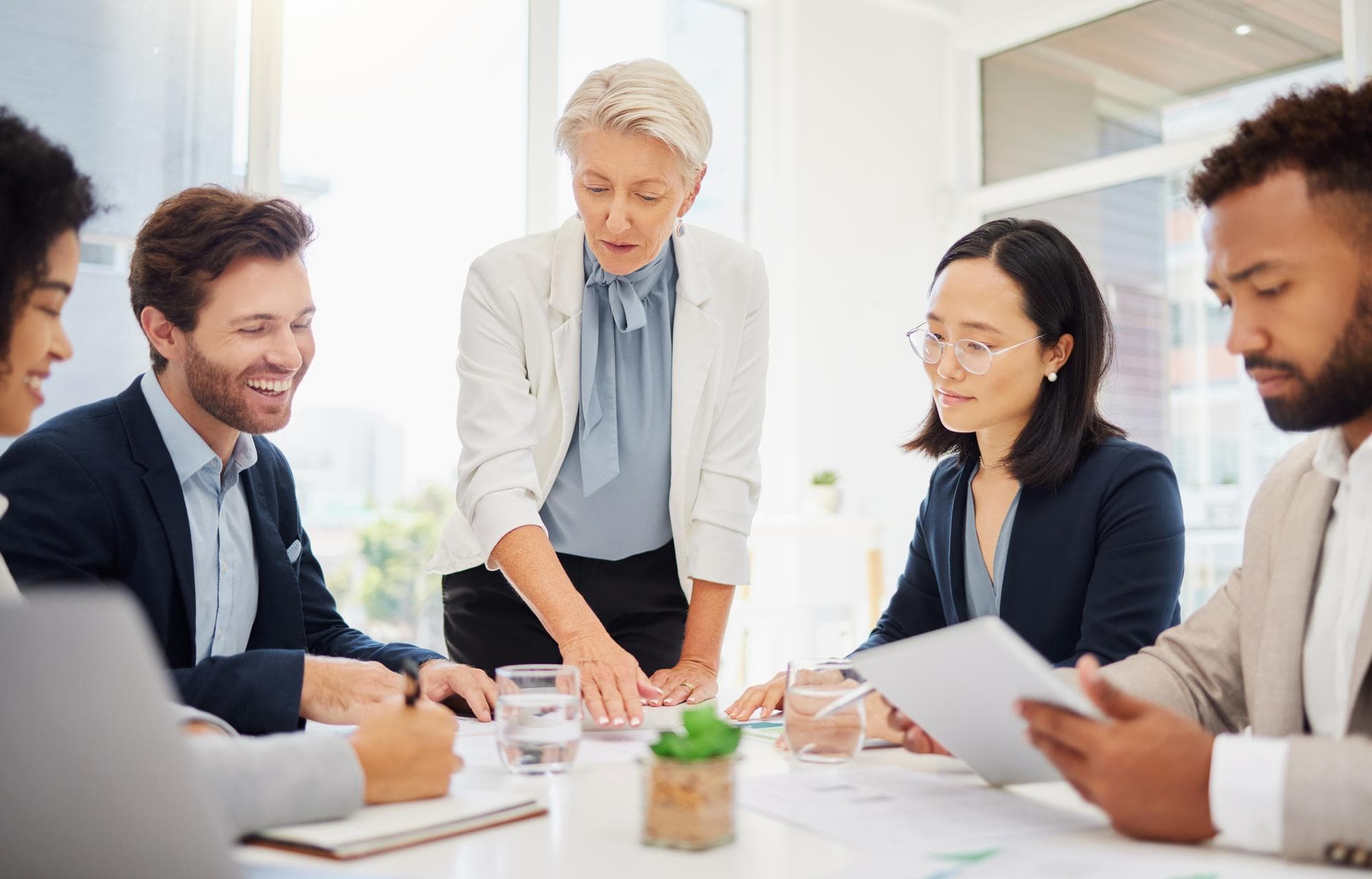 Collaboration meeting and a manager business woman talking to her team in the boardroom for coaching Teamwork leadership and planning with an employee group in the office for a strategy workshop
