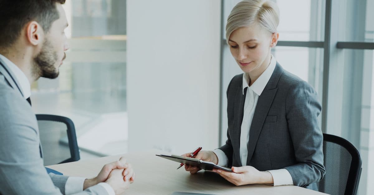 Two professionals in a modern office discussing business. Bright, professional setting.