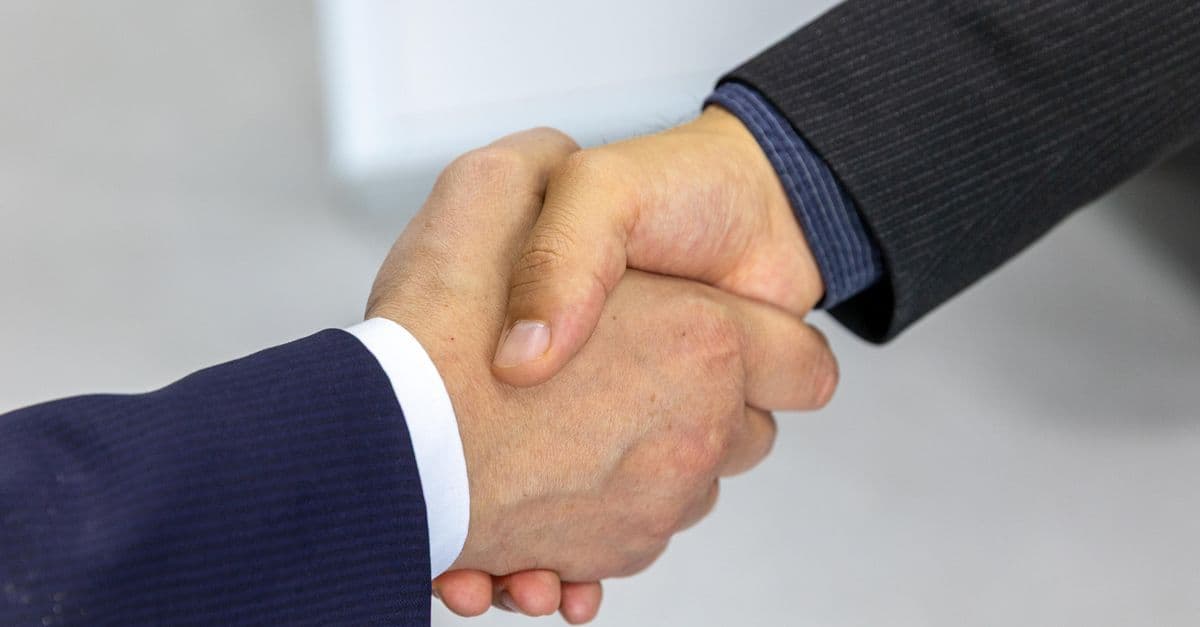 Zwei Geschäftspartner geben sich förmlich die Hand zur Gratulation im Büro