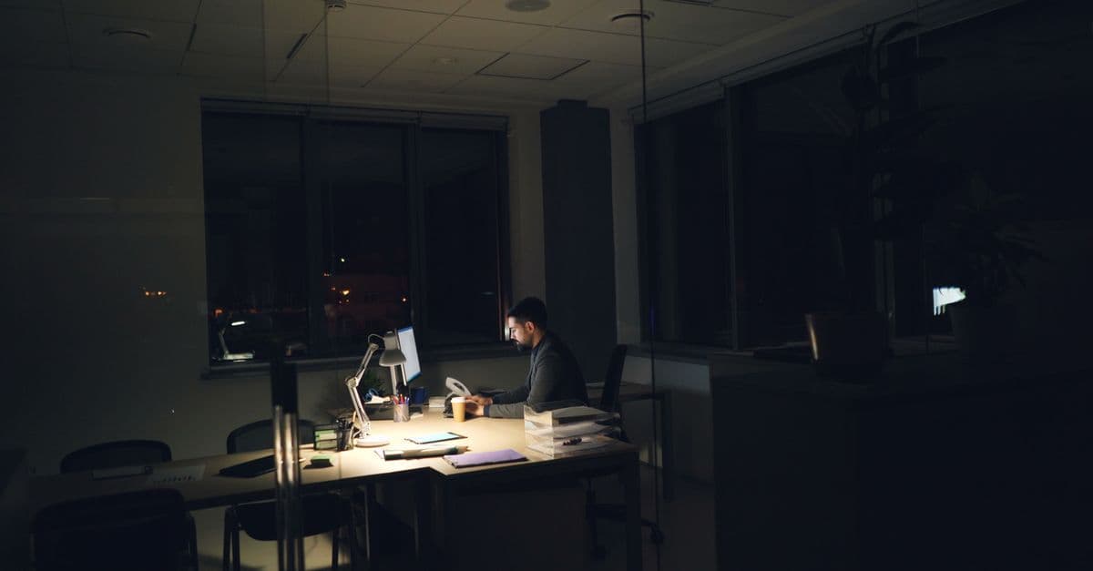 Mitarbeiter arbeitet abends allein im Büro über die vereinbarte Zeit hinaus