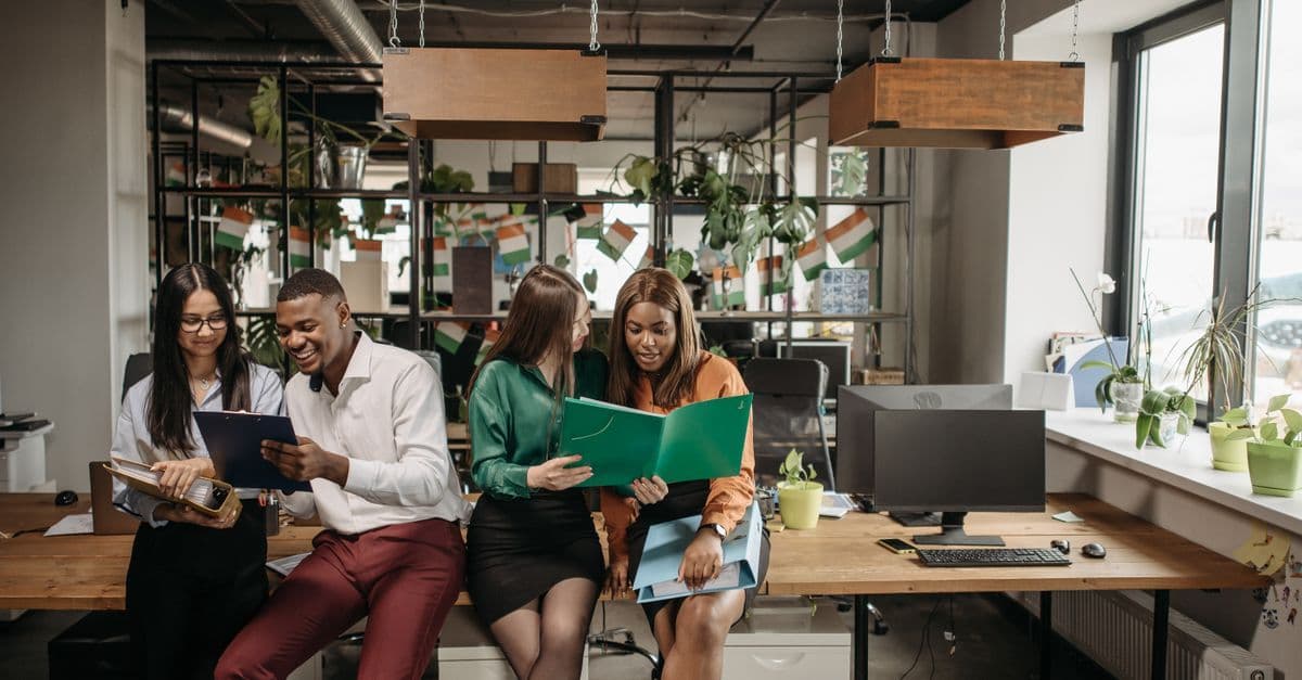 Group of colleagues sharing ideas in a vibrant office environment, promoting team collaboration and diversity.