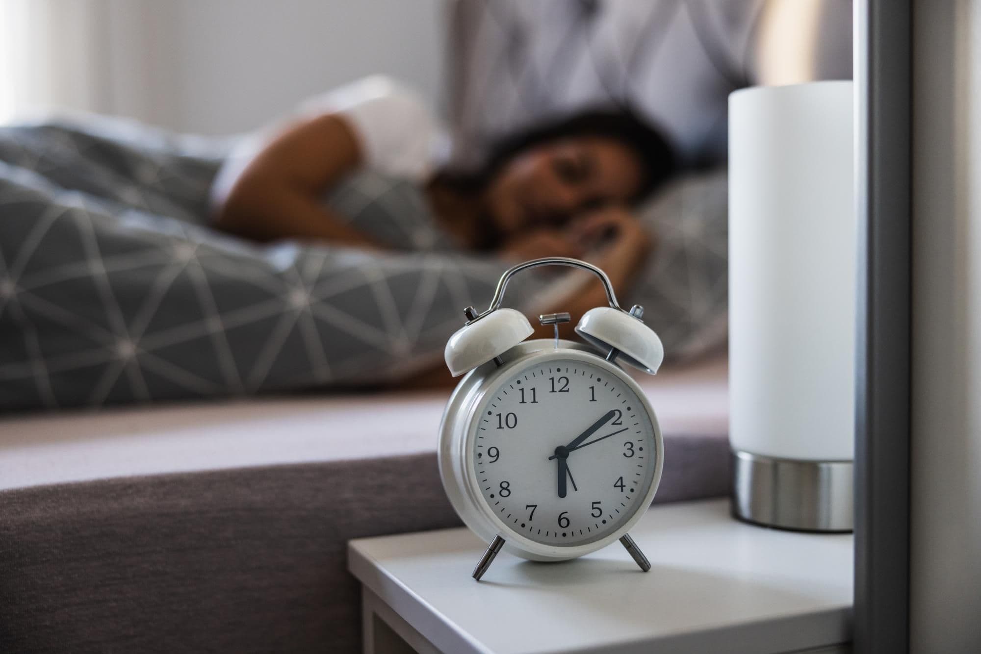 Wecker auf dem Nachttisch symbolisiert die gesetzliche Ruhezeit von elf Stunden zwischen zwei Arbeitstagen